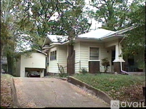 A house with a white garage door is surrounded by trees.