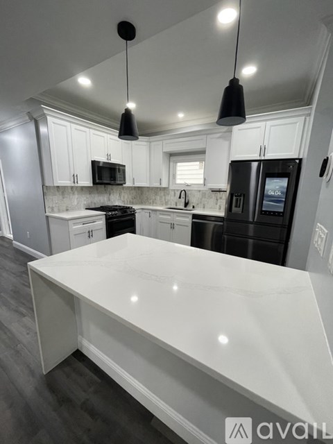 A kitchen with a black fridge and a white counter top.