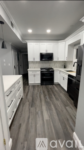 A kitchen with black appliances and white cabinets.