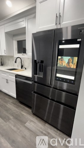A modern kitchen with a black fridge and stainless steel appliances.