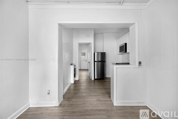 A white kitchen with a refrigerator, microwave, and oven.