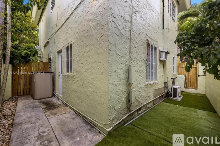 A narrow alley with a white building and a green lawn.