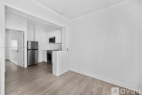 A spacious kitchen with white cabinets and a wooden floor.