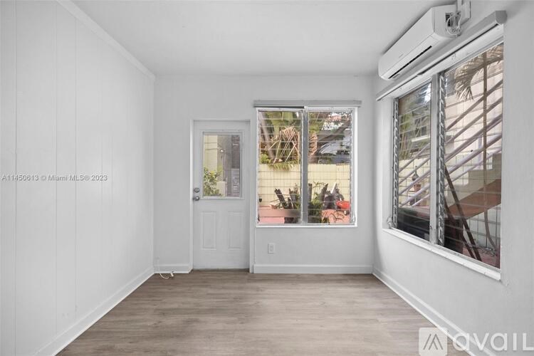 A room with a window showing a balcony with a table and chairs.