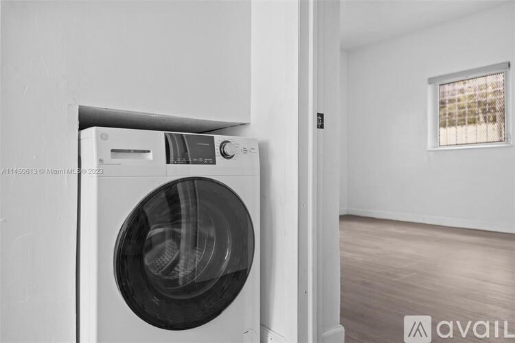 A washing machine is installed in a white wall.