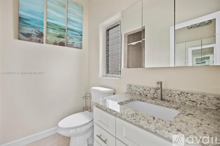 A bathroom with a toilet, sink, and a painting on the wall.