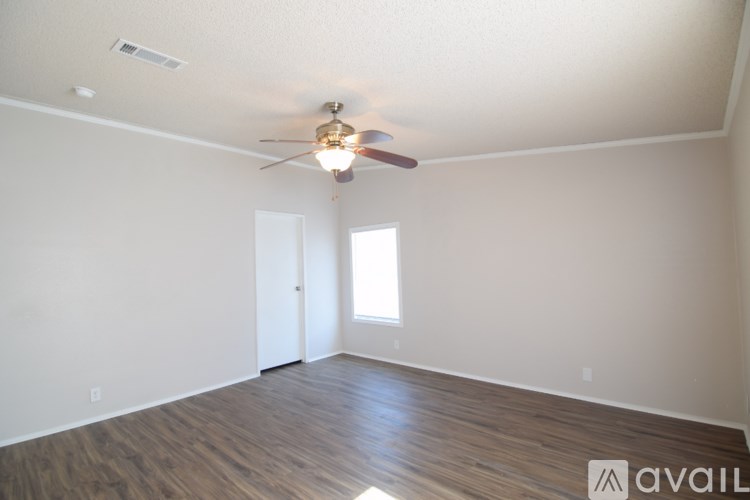 A room with a ceiling fan and wooden flooring.