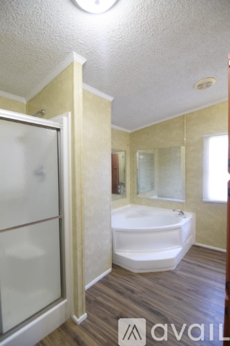 A bathroom with a white tub and wooden floors.