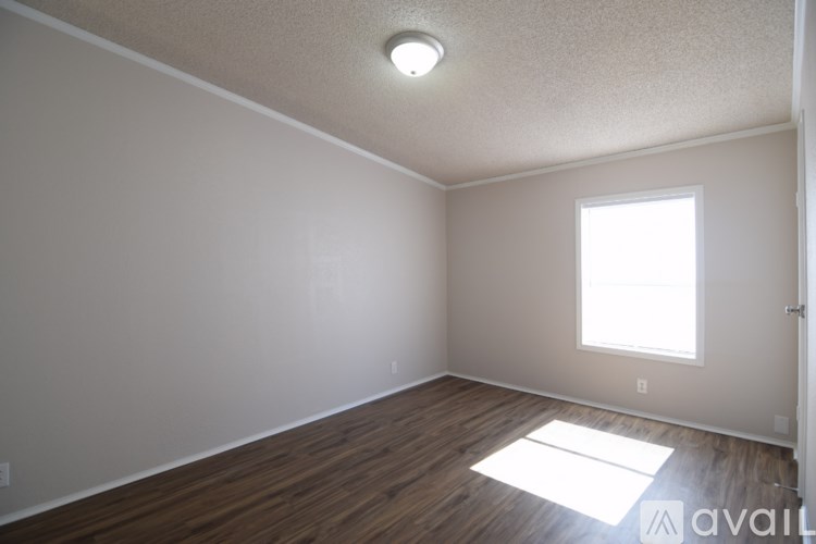 A room with wooden flooring and a window letting in natural light.