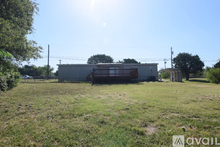 A sunny day in a field with a building and a fence.
