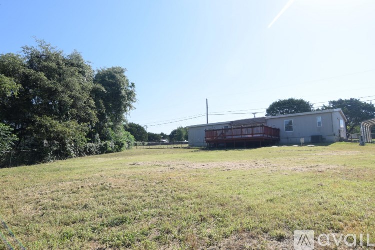 A field with a building and a trailer in the background.
