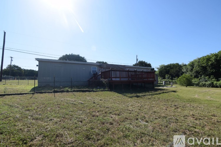 A sunny day with a house and a fence in the foreground.