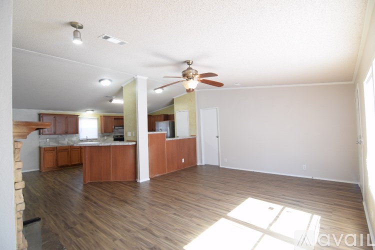 A spacious living room with a ceiling fan and hardwood floors.