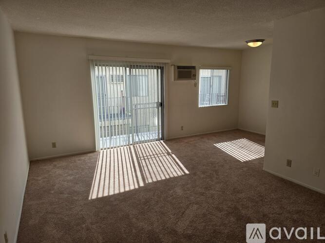 A room with a carpeted floor and a sliding glass door leading to a balcony.
