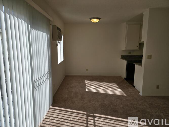 A room with a carpeted floor and a window with blinds.