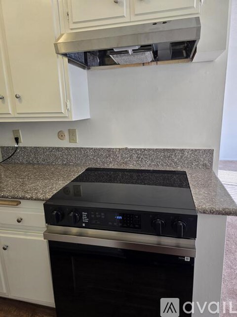 A kitchen with white cabinets and a granite countertop.
