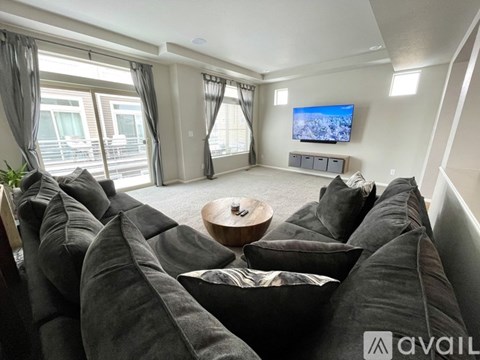 A living room with a grey sofa and a flat screen TV mounted on the wall.