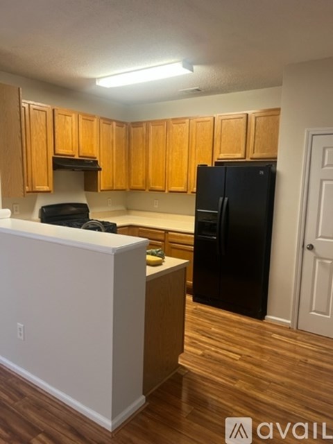 A kitchen with wooden cabinets and a black fridge.