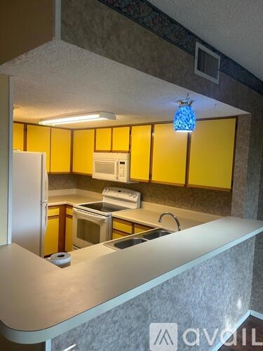 A kitchen with yellow cabinets and a white refrigerator.