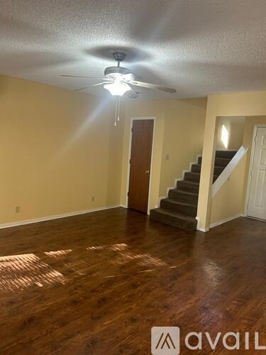 A room with a ceiling fan and wooden flooring.