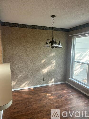 A room with a wooden floor and a chandelier hanging from the ceiling.