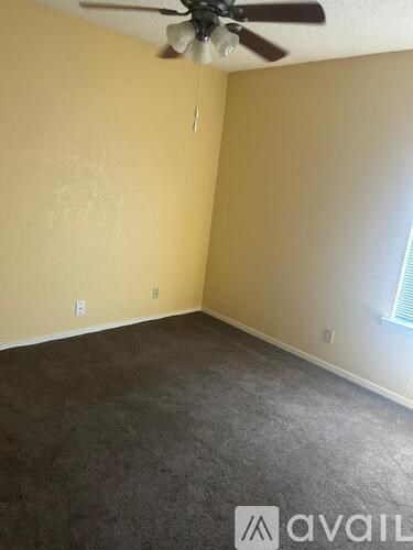 A room with a ceiling fan and carpeted floor.