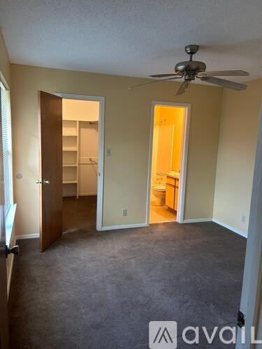 A room with a ceiling fan and two open doors.