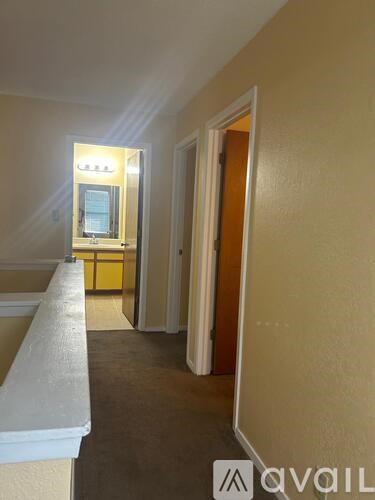 A hallway with a mirror on the wall and a door at the end.