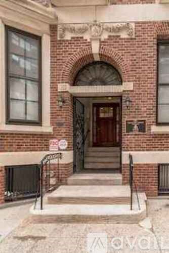 A red brick building with a black iron gate and a "No Parking" sign.