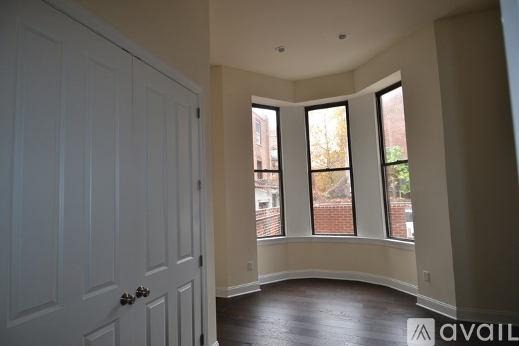A room with a white door and a window showing a view of a brick building.