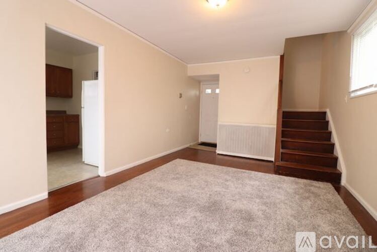 A spacious room with a carpeted floor and a staircase on the right side.