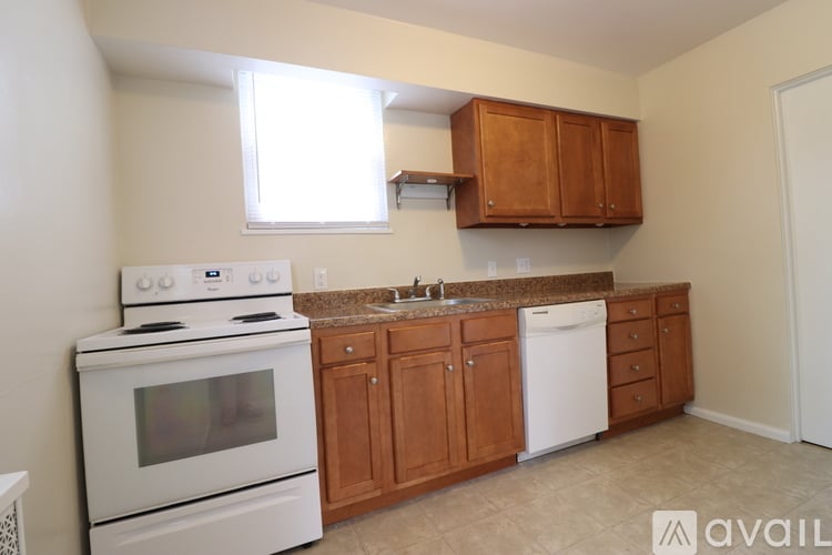 A kitchen with white appliances and wooden cabinets.
