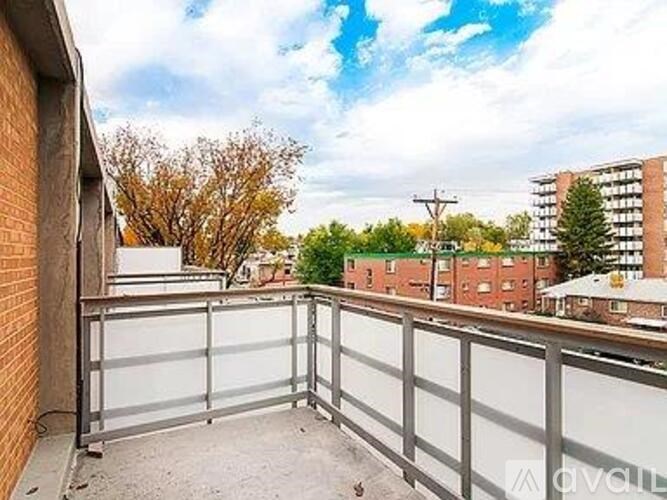 A balcony with a metal railing overlooks a residential area.