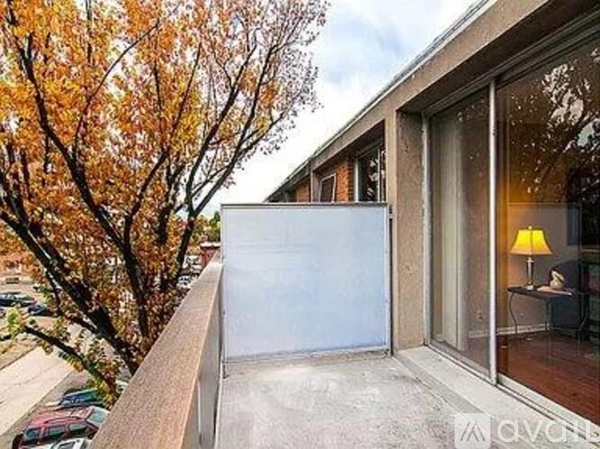 A balcony with a white wall and a tree with yellow leaves.