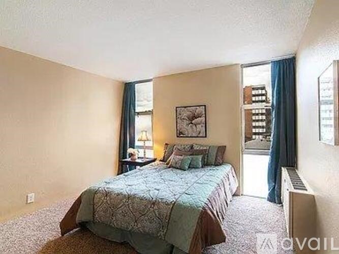 A bedroom with a bed and a window with blue curtains.