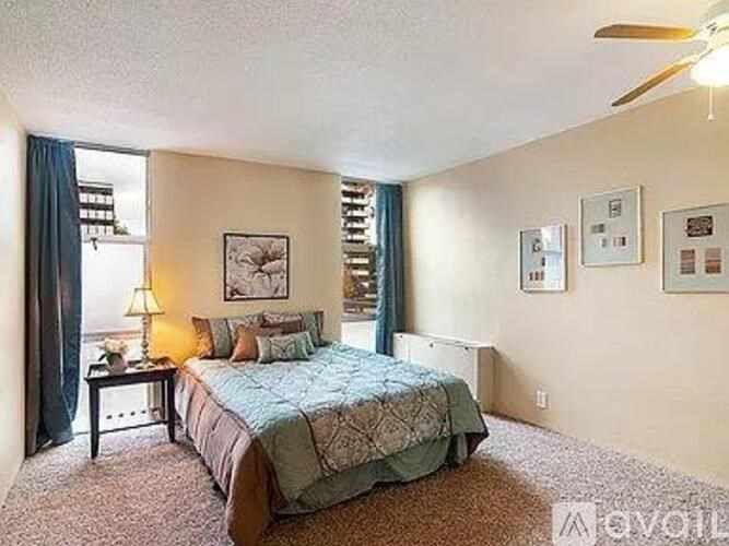 A bedroom with a bed, nightstand, and pictures on the wall.