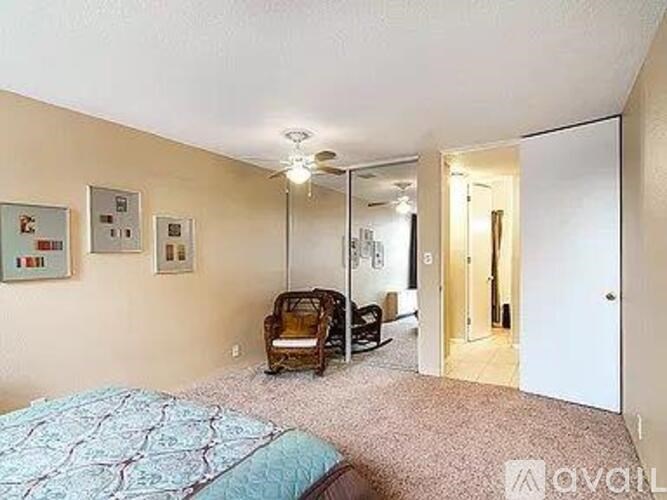 A bedroom with a bed, chair, and mirror.