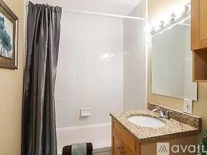 A bathroom with a sink, mirror, and shower.