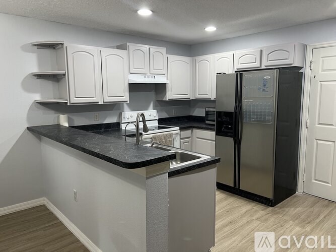 A kitchen with white cabinets and a black countertop.