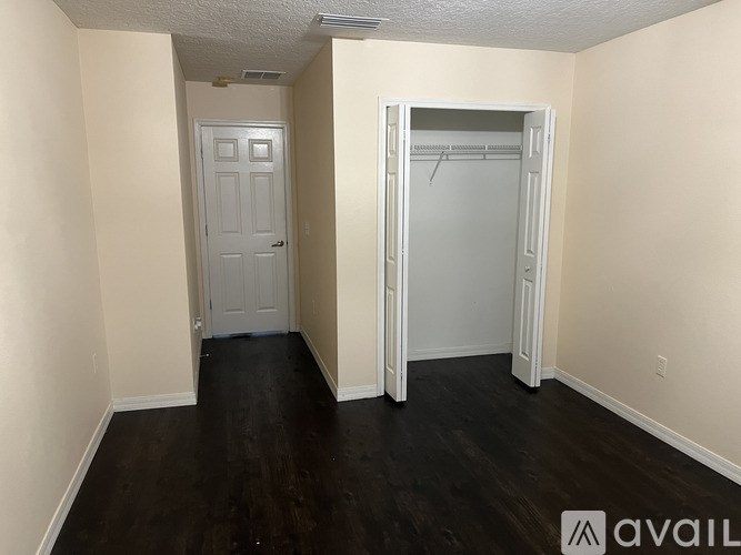 A room with a white door and a white closet with a hanger.