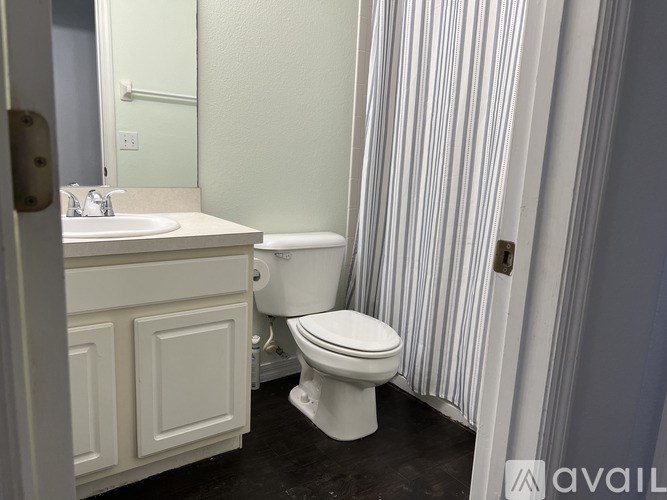 A white toilet is in a bathroom with a sink and a mirror.