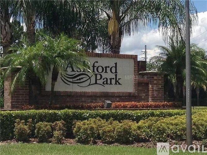 A sign that says "Ashford Park" is in front of some bushes and trees.