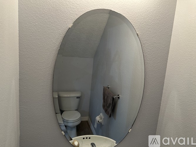 A bathroom with a toilet and a round mirror.