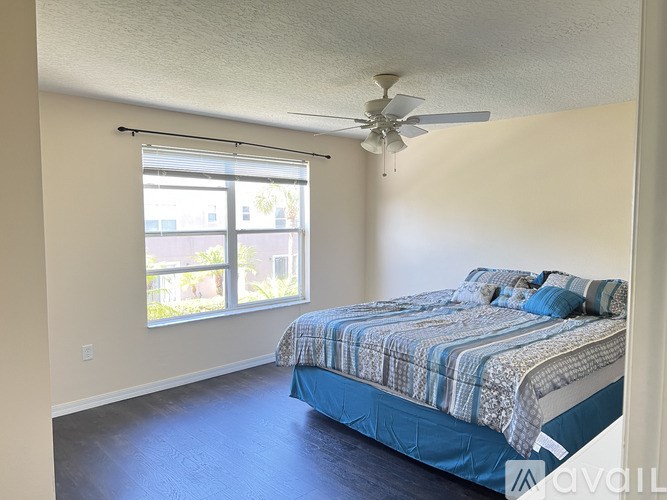 A bedroom with a bed, ceiling fan, and sliding glass doors.