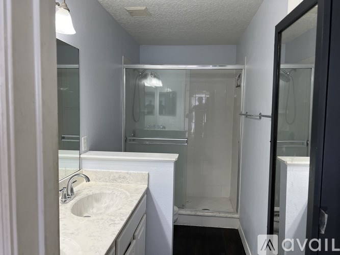 A bathroom with a sink, mirror, and shower.