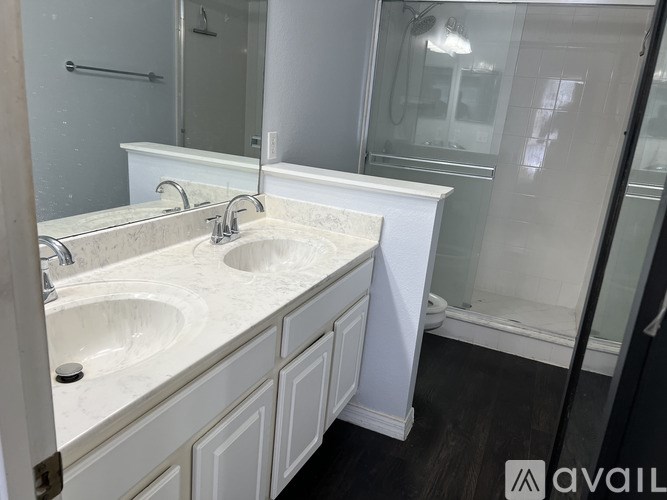 A bathroom with a marble countertop and a glass shower door.