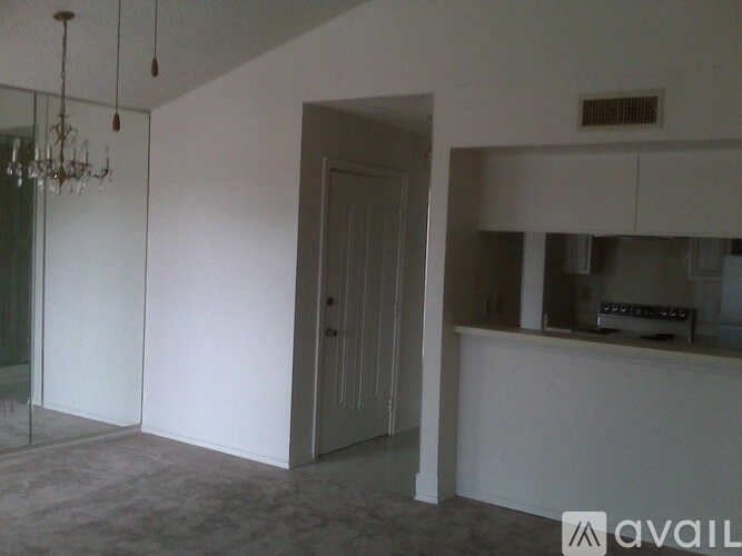 A room with a chandelier, a door, and a counter.