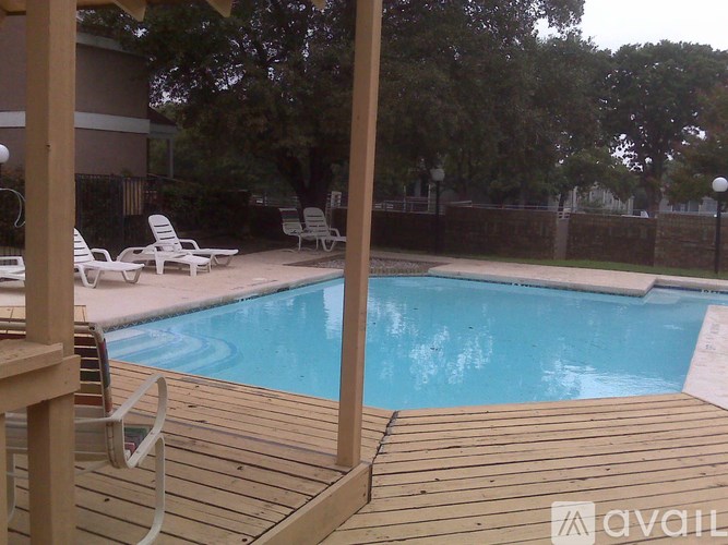 A pool surrounded by a wooden deck and patio furniture.