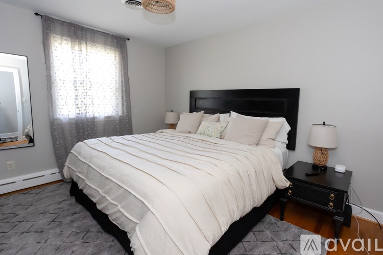 A bedroom with a large bed and a nightstand with a lamp.