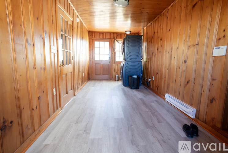 A room with wooden walls and a grey floor with a suitcase on it.